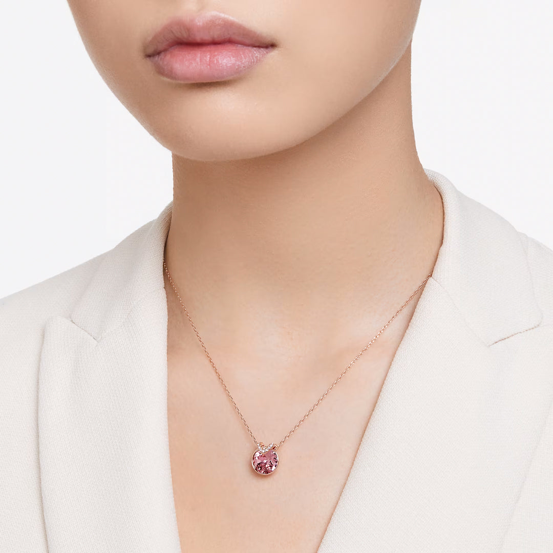 Person wearing a cream top with the Swarovski Bella V Necklace Pendant by Swarovski, featuring rose gold-tone plating and a delicate pink gemstone pendant.