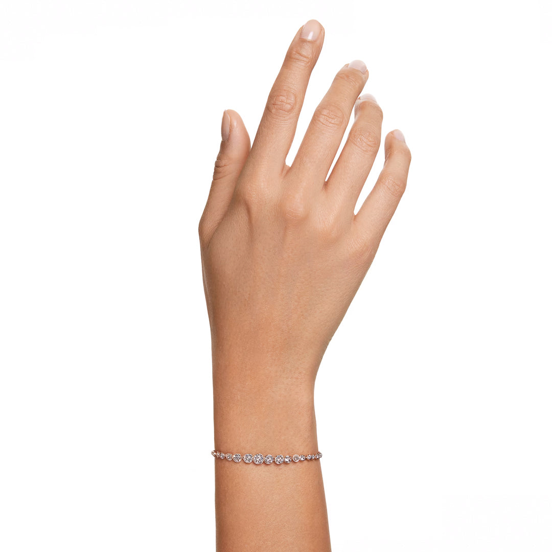 A hand with a light skin tone is shown against a white background, wearing the Swarovski Imber Emily Bracelet in rose gold, embellished with small, sparkling stones.