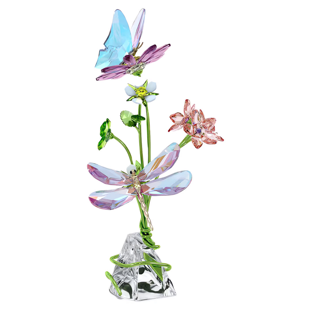 The Swarovski Idyllia Butterfly and Flowers Home Décor piece by Swarovski showcases a captivating design of delicate pink and white flowers with green stems, accentuated by the vibrant blue and purple tones of a butterfly and dragonfly. Set on an exquisite crystal base, it's a stunning addition to any home environment.