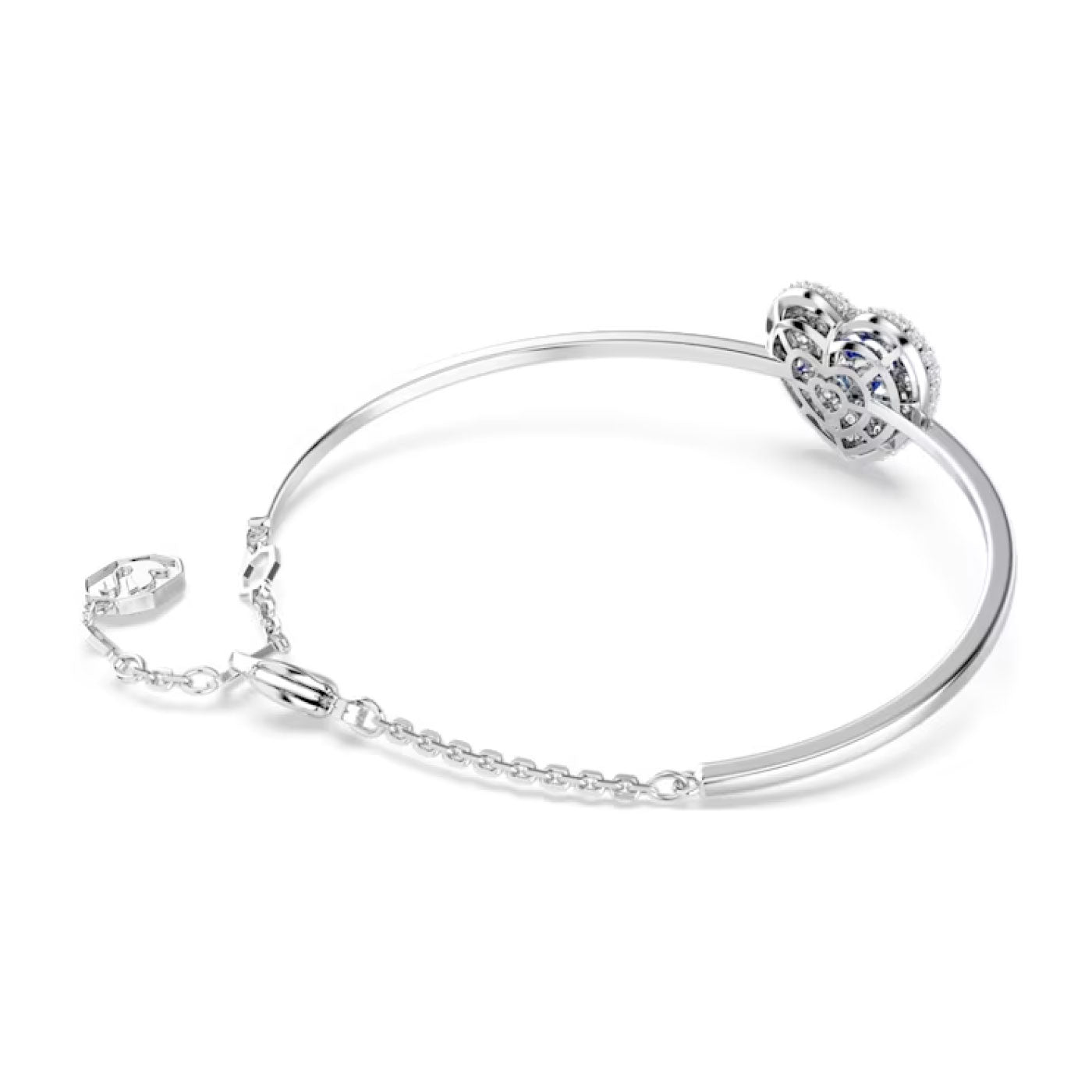 Introducing the Swarovski Hyperbola Heart Bangle: an elegantly designed silver bracelet boasting a circular, intricate heart-shaped charm with a dancing stone and small blue Swarovski Zirconia accents, complete with a chain clasp. The bangle is a testament to refined craftsmanship.