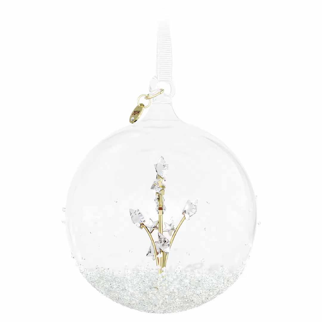The Swarovski 2024 Annual Edition Ball Ornament Home Décor is a clear glass decoration that resembles a festive ball, showcasing a golden branch and crystal-like leaves inside, elegantly suspended from a ribbon. Its base shimmers with sparkling, glittery material typical of an Annual Edition ornament.