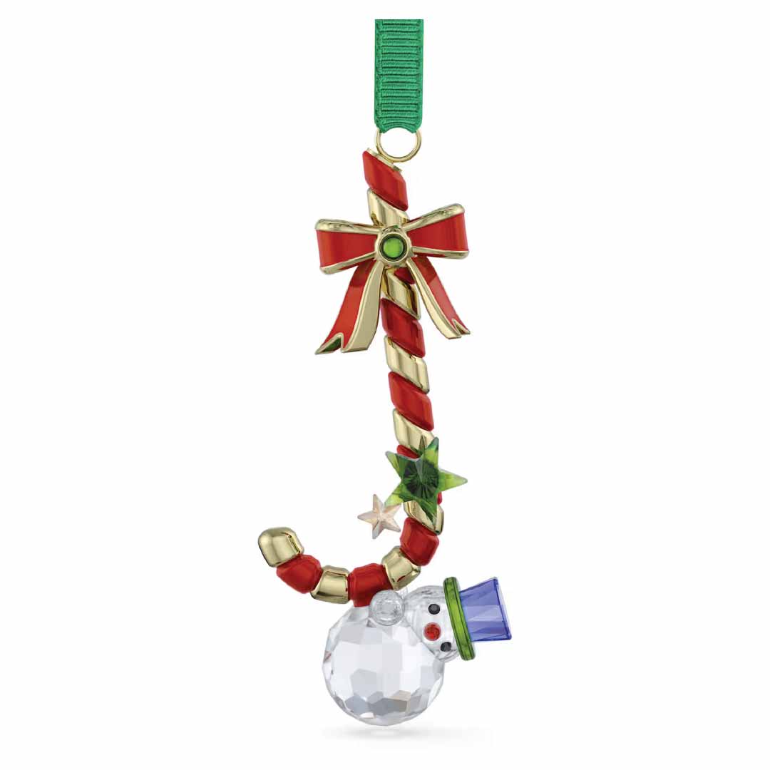 Introducing the Swarovski Holiday Cheers Dulcis Candy Cane Ornament: a delightful crystallized candy cane accented with a red and gold bow, a green star, and completed with an endearing snowman in a blue hat at the base. This exquisite creation by Swarovski is beautifully hung from a green ribbon, adding seasonal charm to any decor.