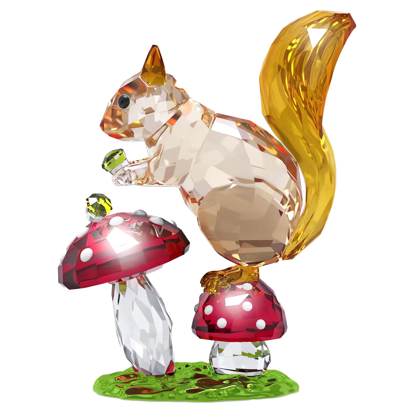 The Swarovski Idyllia Squirrel and Mushrooms Home Décor showcases a beautifully crafted crystal decoration featuring a squirrel figurine with a golden tail perched on vibrant red and white mushrooms. The squirrel is holding a green nut, while the base resembles lush green grass, all intricately designed from faceted crystal as part of the renowned Swarovski brand's Idyllia collection.