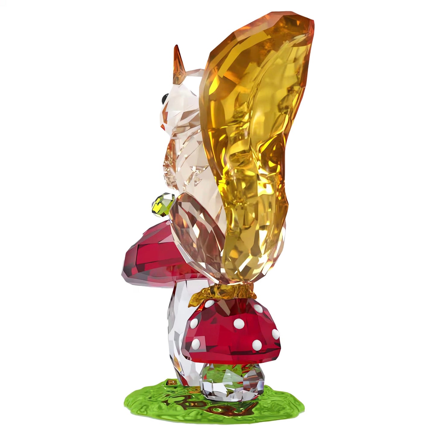 The Swarovski Idyllia Squirrel and Mushrooms Home Décor piece captures a crystal squirrel on a grassy surface, its bushy tail gleaming in the light. With an acorn grasped beside a red mushroom adorned with white spots, it forms an enchanting addition to any setting.