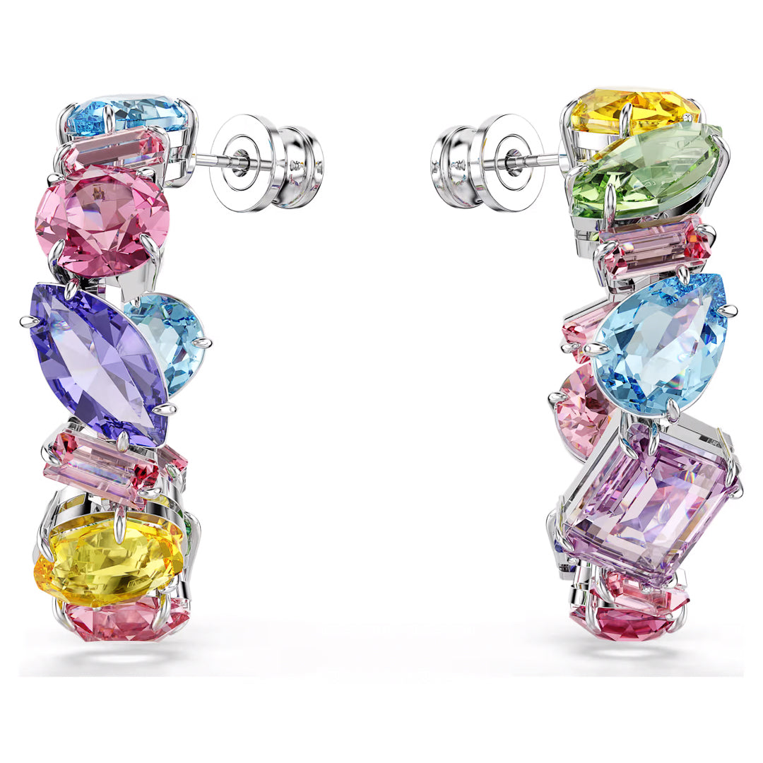 Elevate your style with the Swarovski Gema Multicoloured Hoop Earrings. These exquisite pieces boast asymmetrical pierced designs embellished with a stunning array of crystals and gemstones. The vibrant hues of pink, blue, yellow, and green are beautifully set in silver, creating a captivating visual masterpiece by Swarovski.