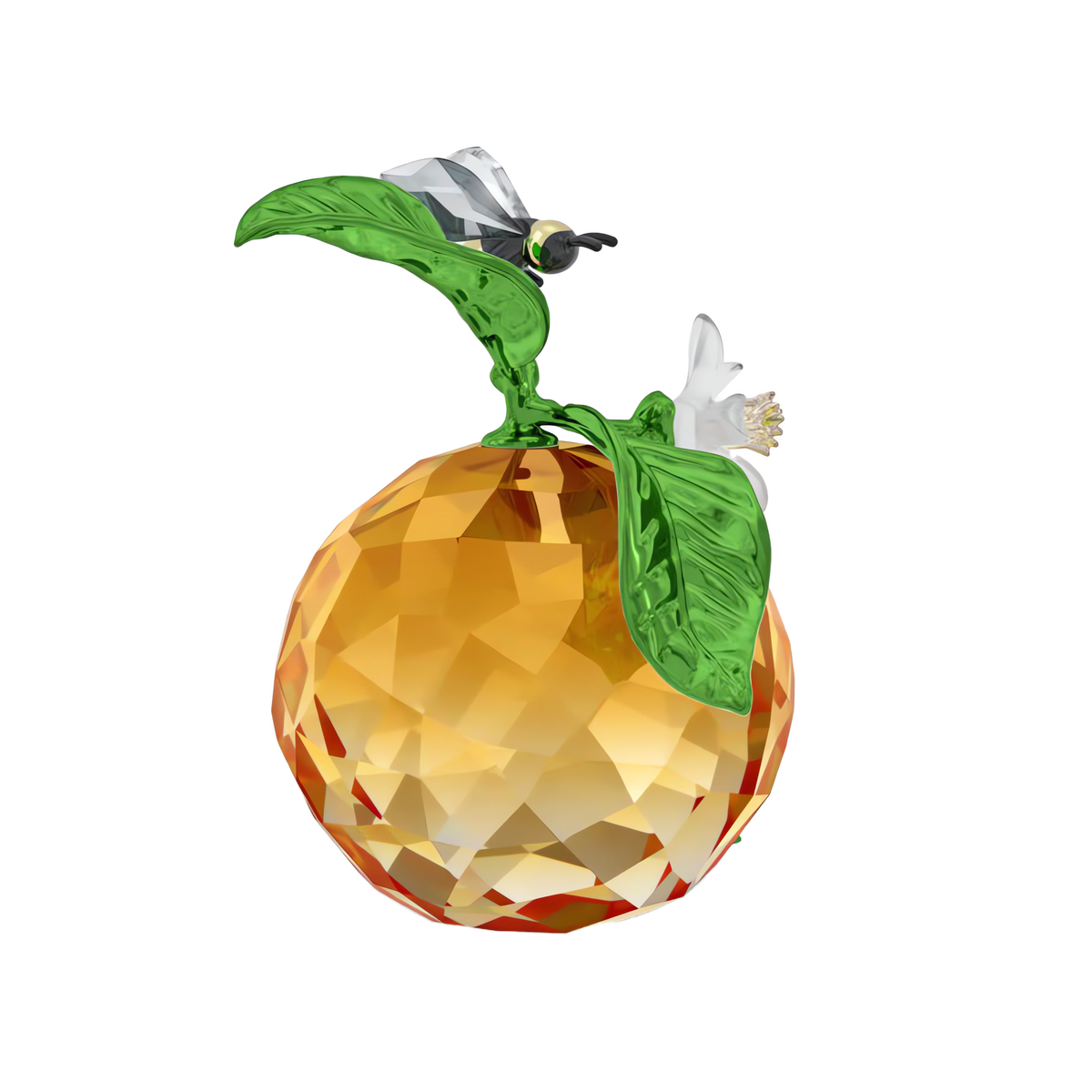 The Swarovski Idyllia Clementine and Bee showcases a faceted crystal orange reminiscent of a decorative clementine, adorned with a green leaf, white blossom, and an exquisite crystal bee figurine perched on top. This sparkling piece from Swarovski’s Idyllia collection is set against a plain white background.