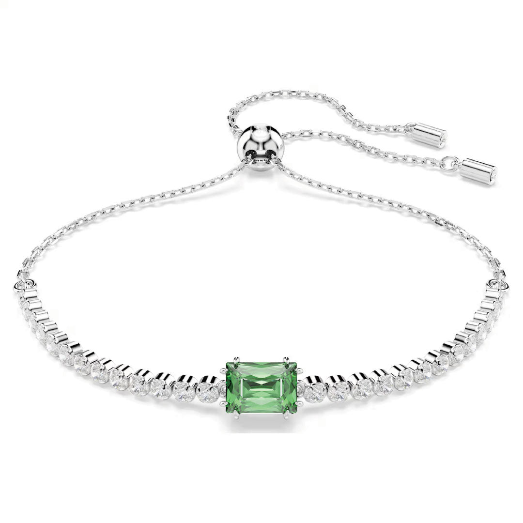 The Swarovski Matrix Tennis Bracelet, crafted by the renowned brand Swarovski, is a graceful rhodium-plated silver piece showcasing a central emerald-cut green gemstone encircled by petite clear stones. This elegant bracelet is embellished with shimmering Swarovski Zirconia and includes an adjustable chain with a smooth sliding clasp for a perfect fit.