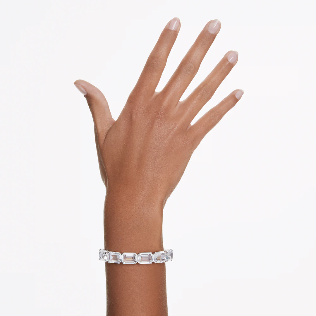 A hand is displayed wearing the exquisite Swarovski Millenia Bangle, showcasing octagon-cut crystals in an elegant silver setting against a plain white background.