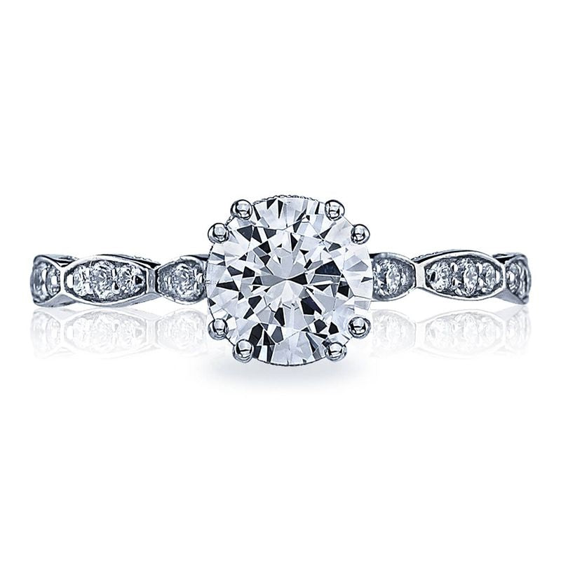 The Tacori Sculpted Crescent 18K White Gold Round Brilliant Solitaire Semi Mount with Diamond Band engagement ring features a prominent round diamond in the center, complemented by smaller diamonds embellishing the band and intricate patterns along the sides, enhancing its sophisticated and detailed design.