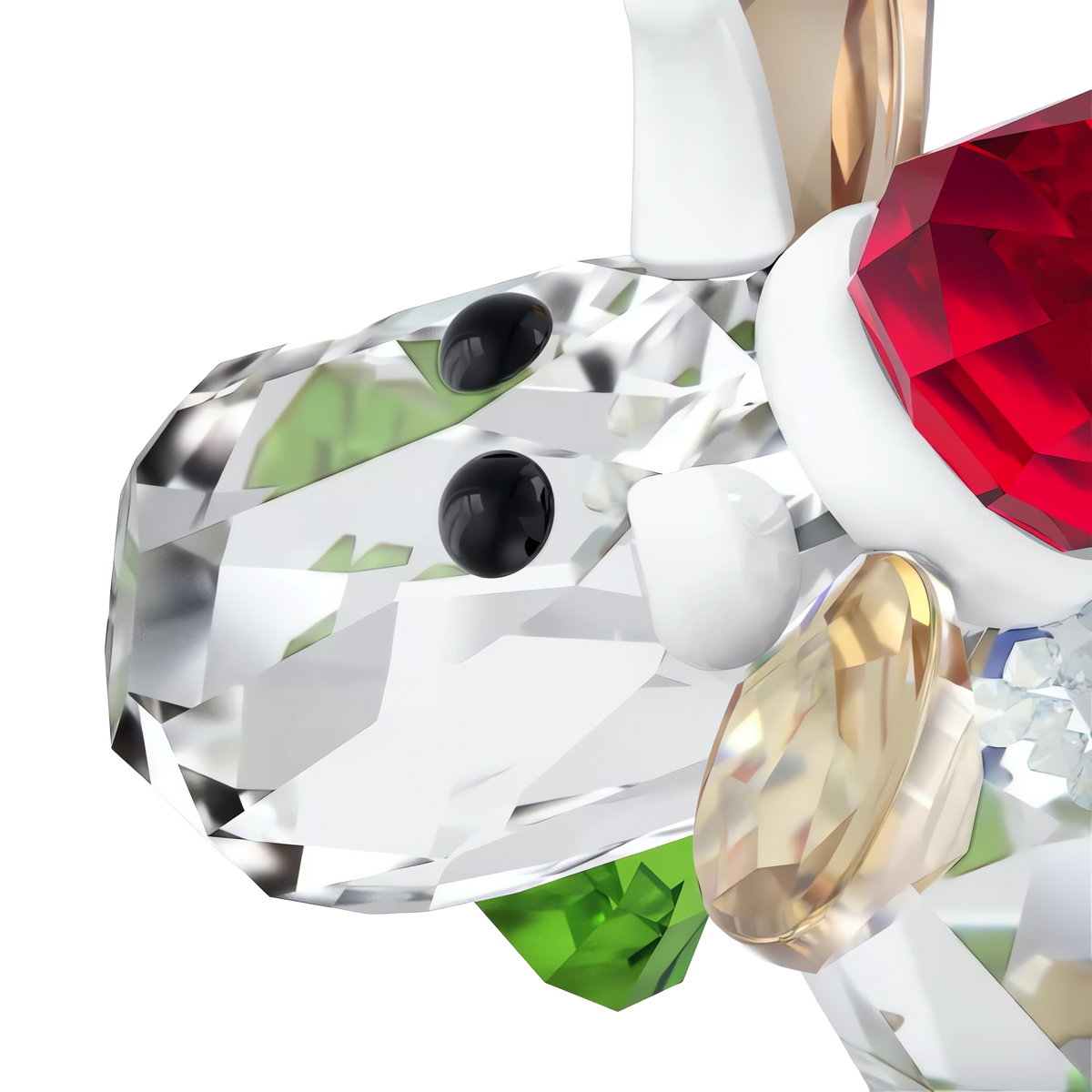 A close-up of the Swarovski Mo Holiday Annual Edition 2025 crystal figurine by Swarovski, shaped like a reindeer with a red crystal accent, gold and green details, and black eyes, set against a white background. This charming piece is part of the beloved Swarovski Mo Holiday series.