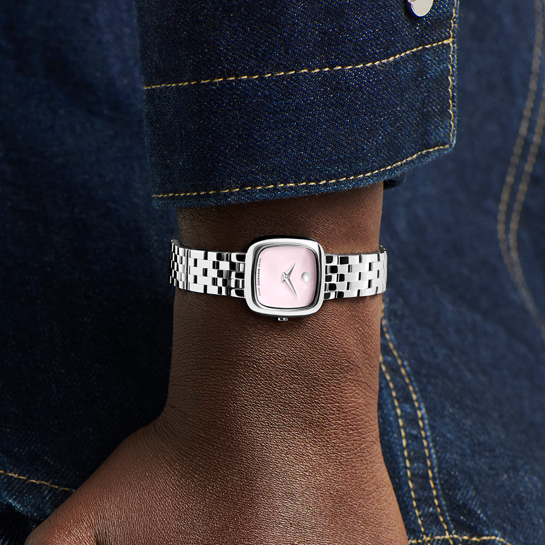 Movado Museum Classic Quartz 22mm x 22mm watch with a square-faced light pink Museum Dial and a silver-tone multi-link metal bracelet on a wrist.