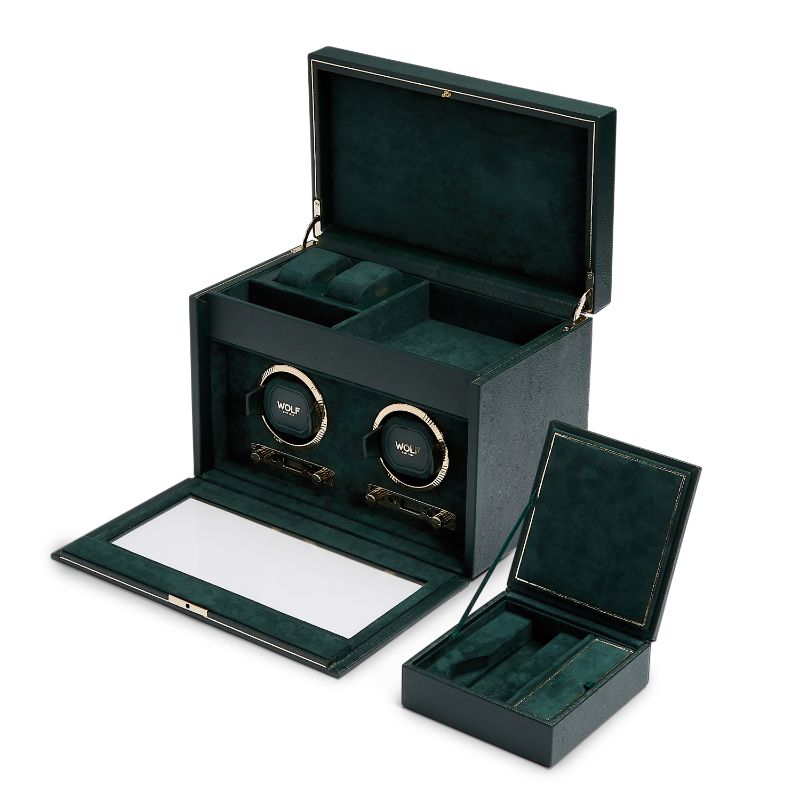 A WOLF 1834 British Racing Green Double Winder in vegan leather is displayed open, revealing its dual watch compartments beneath the glass lid. Next to it, there is a smaller matching jewelry box featuring sections for rings and accessories.
