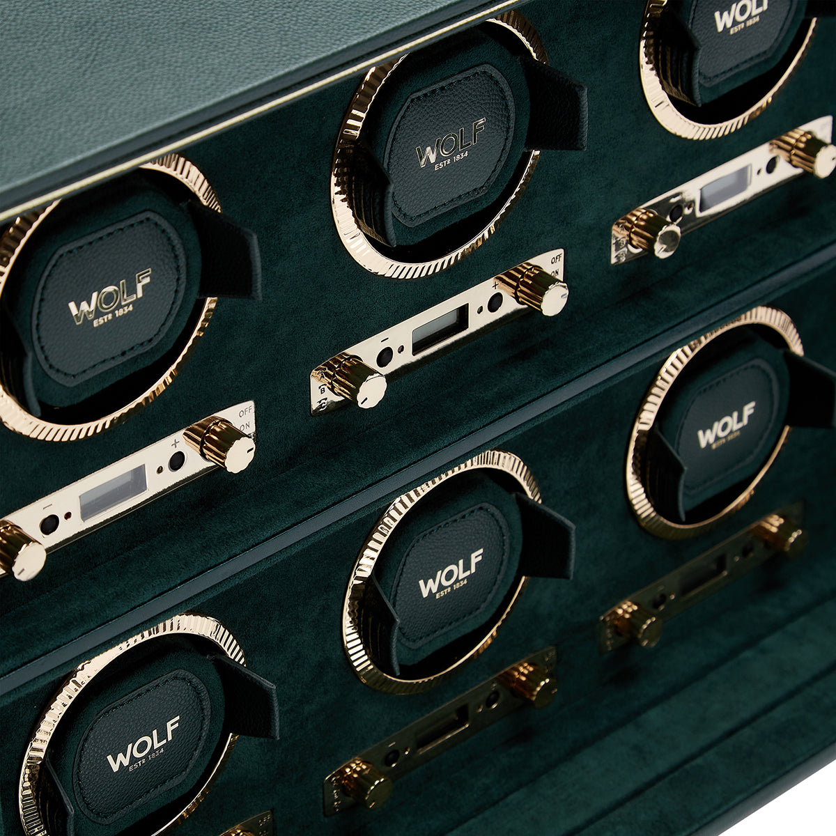 Presenting the WOLF 1834 British Racing 8PC Watch Winder, a luxurious display case that embodies patented innovation. It features eight compartments, each elegantly marked with "WOLF 1834." The watch winder is adorned with gold accents and control knobs offering various rotation options, complemented by a sophisticated green velvet interior.