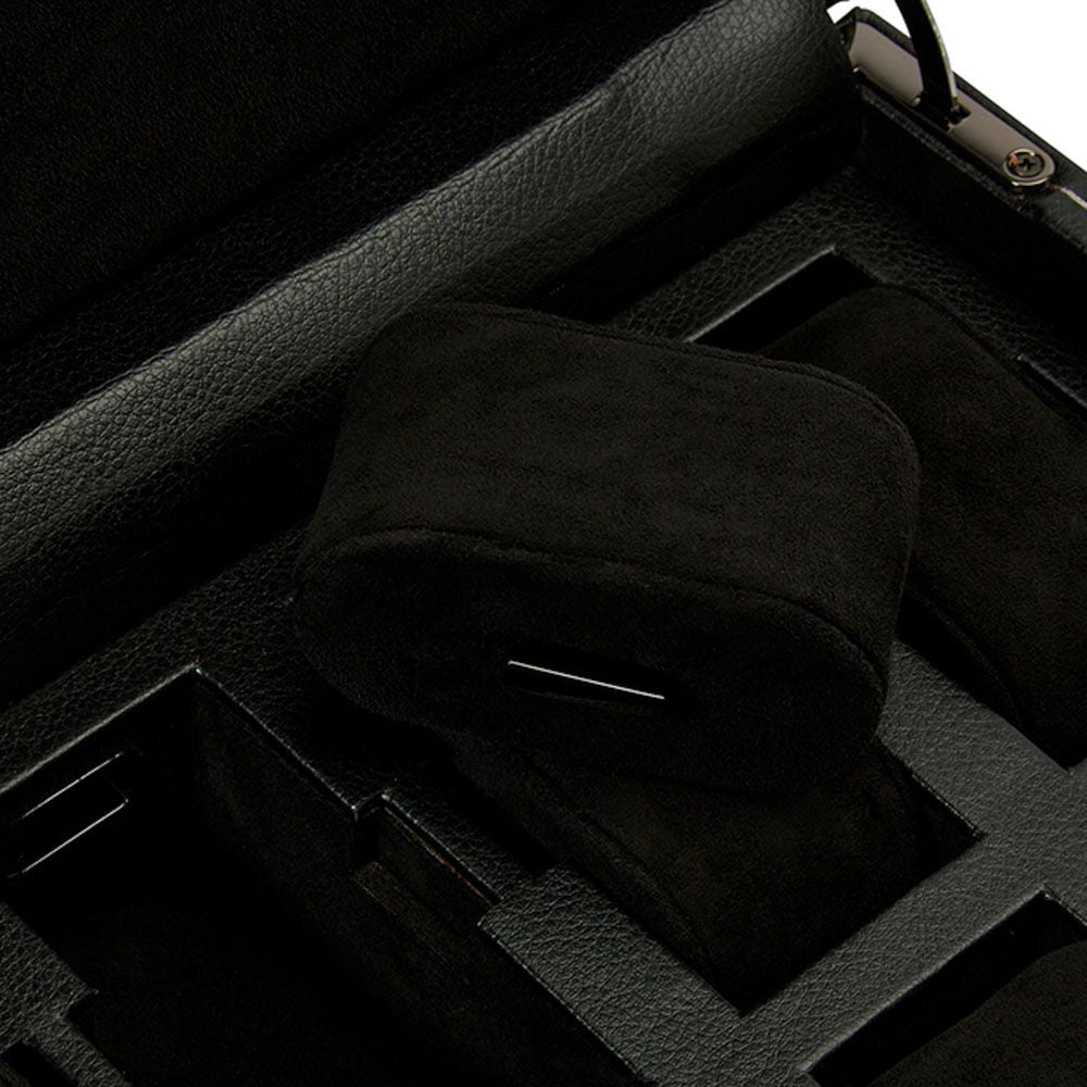 The close-up reveals the open WOLF 1834 British Racing 10 Piece Watch Box, showcasing a sleek black vegan leather exterior and a plush velvet interior. It is designed with multiple compartments, some of which hold soft, rectangular cushions ideal for watch storage. The focus is on the rich textures that flawlessly combine luxury with practicality.