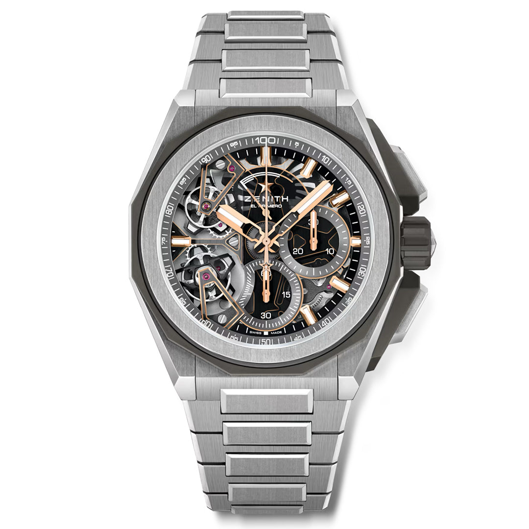 The ZENITH Defy Extreme El Primero 9020 is a luxury watch by Zenith, featuring a silver skeleton dial with intricate gears inside a sleek titanium case. It includes gold and silver accents, a metal link band, and has gold hour and minute hands with a prominent crown on the right side.
