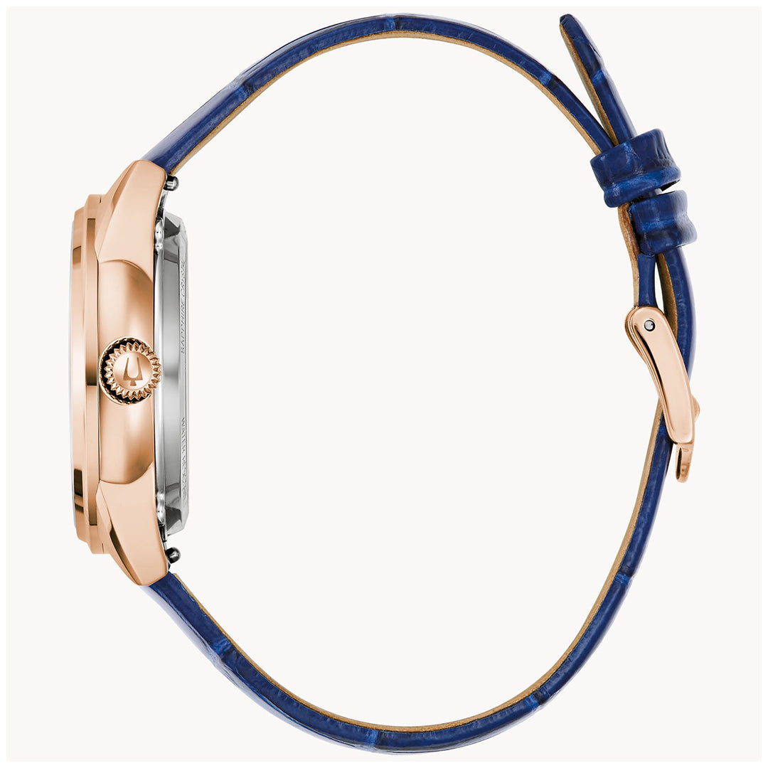 The side view of the Bulova Sutton Classic Automatic 34.5mm Watch showcases a rose gold case, textured crown, and blue leather strap with a buckle fastening, while the face of this elegant timepiece stays just out of sight.