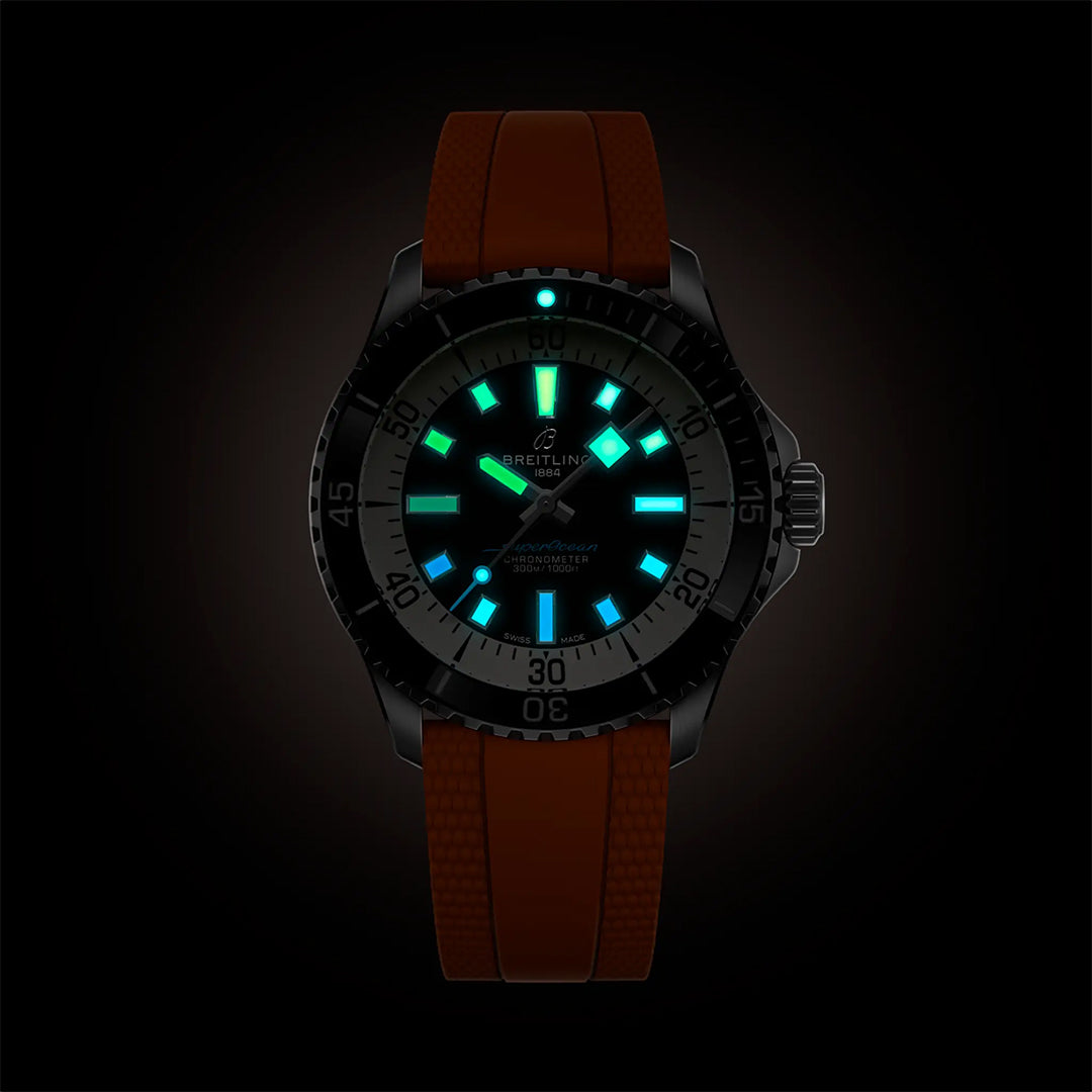 The BREITLING Superocean Automatic 42 by Breitling features a red textured strap, black bezel, and a luminous watch face with blue and green indexes, ensuring easy readability in the dark.