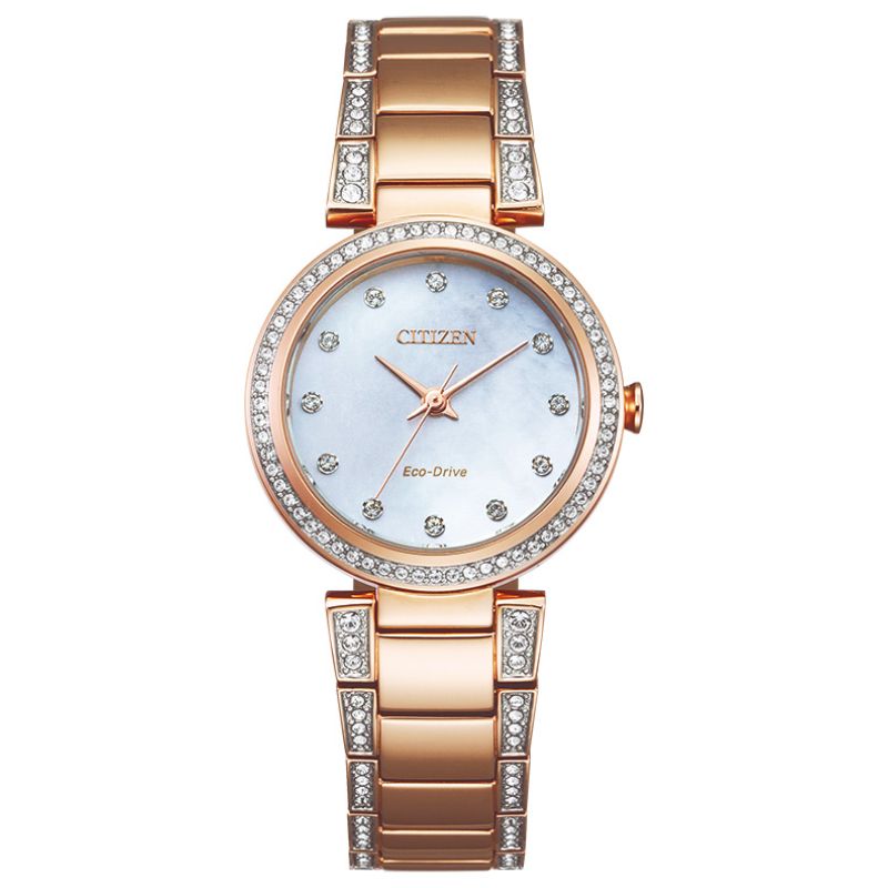 The CITIZEN Silhouette Crystal Eco-Drive 28mm Watch is a rose gold timepiece from the brand CITIZEN, featuring a mother-of-pearl face. It boasts Swarovski crystals as diamond accents on the bezel and bracelet links, along with crystal hour markers on the dial. The bracelet is polished for timeless elegance.
