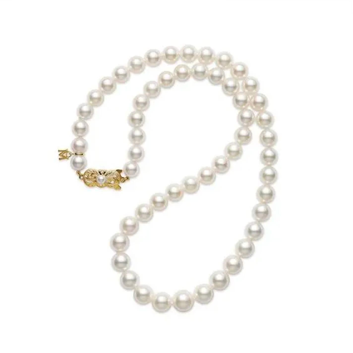 The Mikimoto 18-inch Akoya Cultured Pearl Graduated Strand Necklace features round, evenly sized pearls arranged in a gentle curve, complemented by an intricately detailed 18K yellow gold clasp for a classic and elegant appearance.