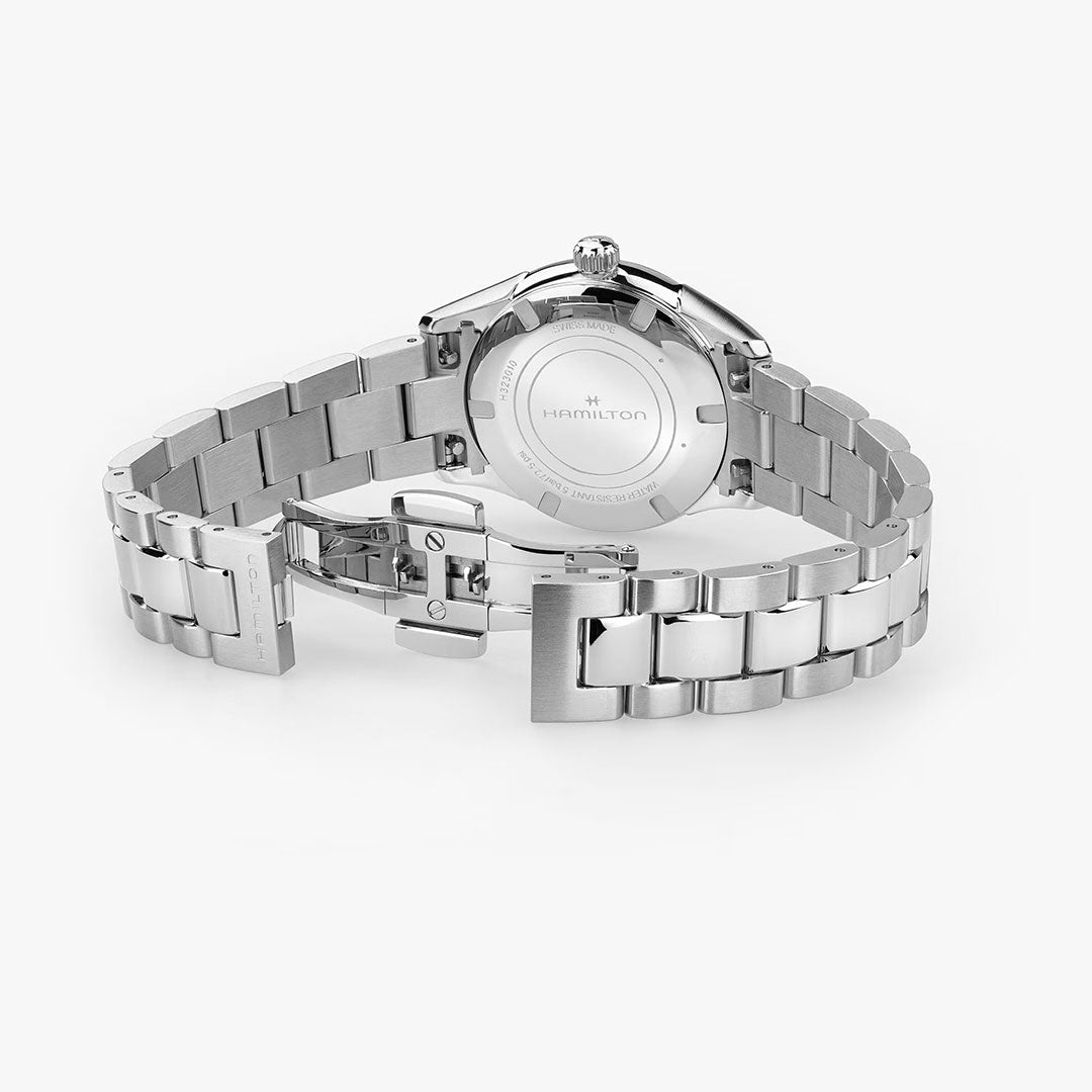 A Hamilton Jazzmaster Quartz 32mm Watch is displayed from the back, featuring the Hamilton Watch branding on the case and an open deployment clasp on its stainless steel metal link bracelet.