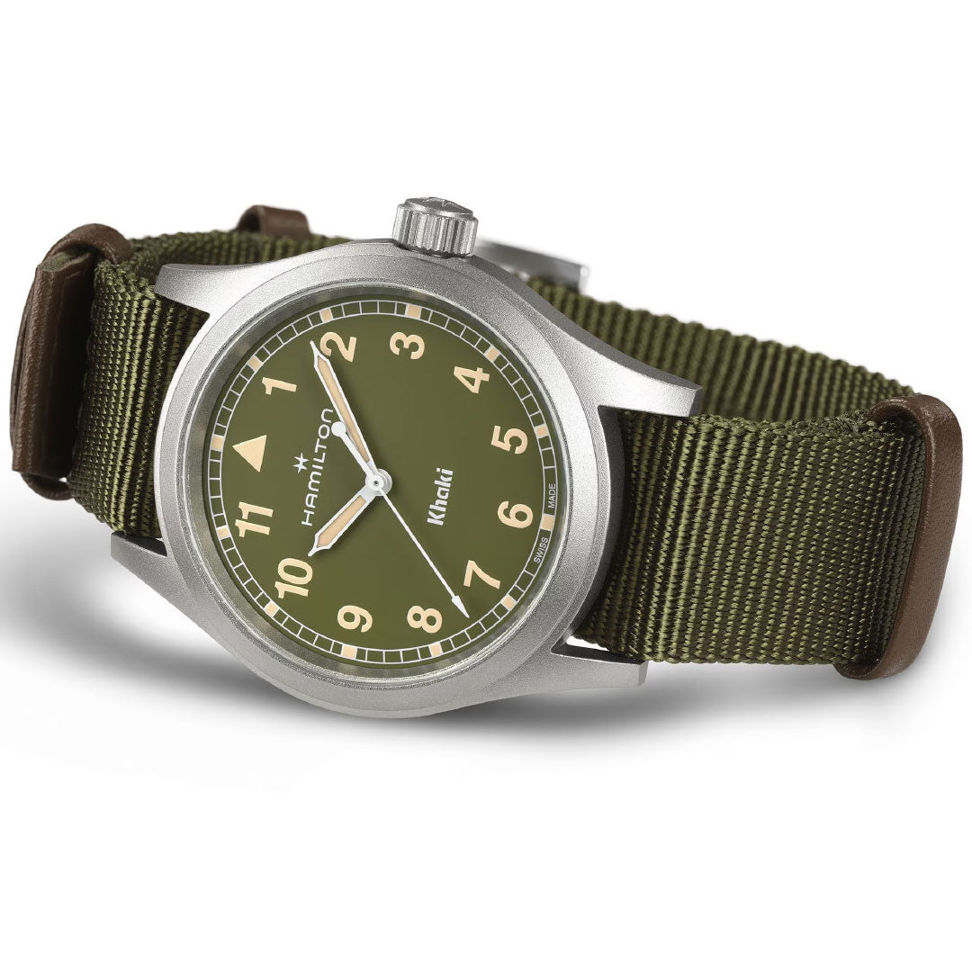 The Hamilton Watch Khaki Field Quartz 38mm features a khaki green dial, beige numerals, and a nylon strap with brown leather accents, shown angled.