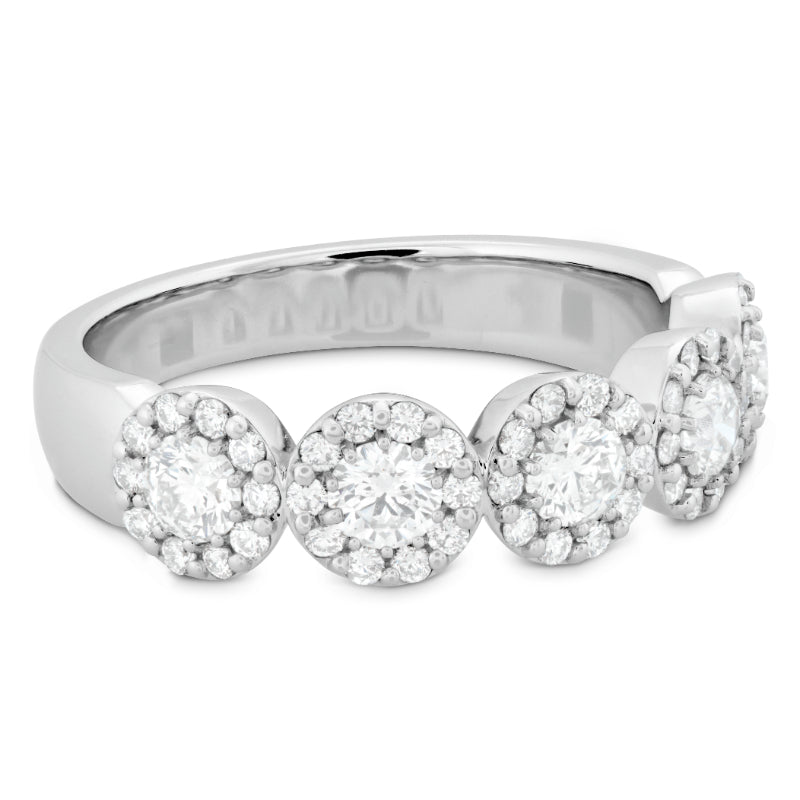 The Hearts On Fire Fulfillment 18K White Gold Round Brilliant Diamond Anniversary Ring is a stunning diamond jewelry piece. It features four large round diamonds, each encircled by smaller stones for a halo effect, and is crafted in sleek 18 karat white gold that enhances its brilliance.