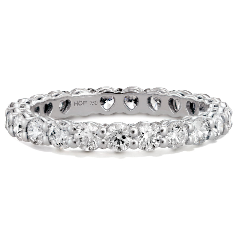 The Hearts On Fire Multiplicity Round Brilliant Diamond Eternity Ring, crafted by Hearts on Fire, elegantly encircles the finger with its white gold band adorned with round brilliant diamonds and charming heart-shaped cutouts along the inner side.