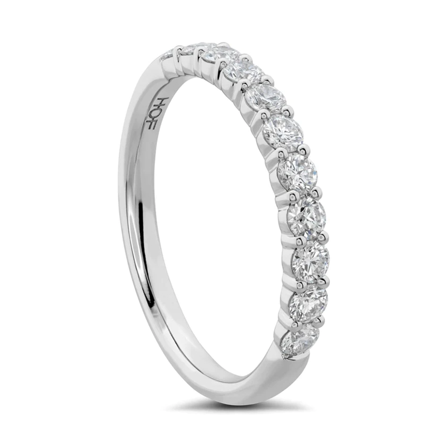 Introducing the Hearts On Fire Signature 18K White Gold Round Brilliant Diamond Anniversary Ring by Hearts on Fire. This exquisite piece features a silver band set with a row of round, sparkling diamonds. The inside of the band is engraved with "HOF," exuding a sleek and elegant design that encapsulates timeless elegance.
