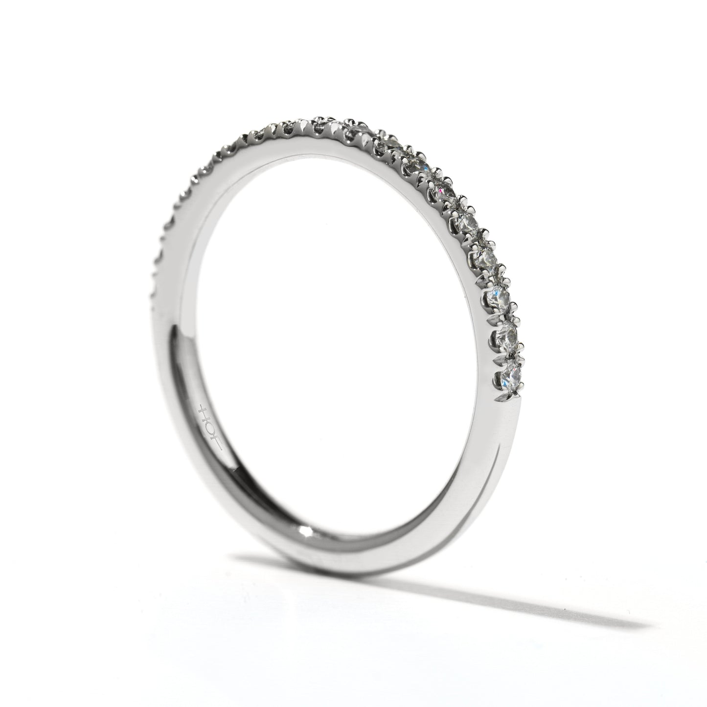 The Hearts On Fire Transcend Platinum Round Brilliant Diamond Anniversary Ring is a simple, elegant piece crafted in platinum. It features small, sparkling gemstones around its top half, reminiscent of a classic Hearts on Fire design. Displayed on a white background, the ring's sleek design and the brilliance of the stones are perfectly highlighted.