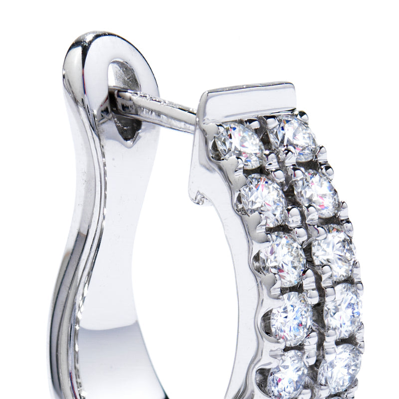 The Hearts On Fire HOF Classic Hoop Earrings, crafted by the renowned brand Hearts on Fire, feature a stunning close-up of a white gold hoop adorned with two rows of sparkling white stones. The earring's polished and shiny finish beautifully highlights the brilliance of the faceted stones, exemplifying the elegance of these classic double row hoop earrings.