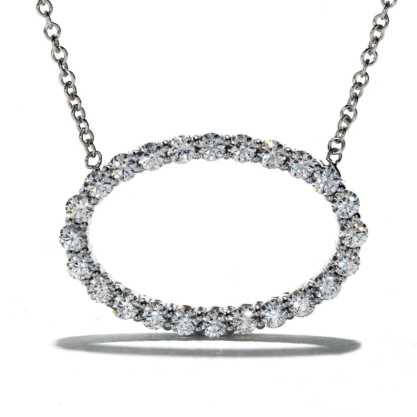 A Hearts On Fire Whimsical 18K White Gold Pendant, featuring an oval design of impeccably arranged diamonds, gleams brilliantly. Suspended by a delicate chain, this luxurious piece showcases elegance and brilliance against its backdrop.