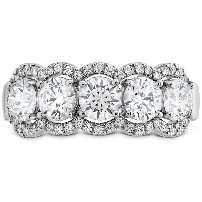 The Hearts On Fire Aurora 18K White Gold Round Brilliant Diamond Fashion Ring showcases an exquisite design by Hearts on Fire. It features a silver band adorned with five large round diamonds, each beautifully surrounded by a halo of smaller diamonds to enhance their sparkle. The band further shimmers with additional smaller diamonds, adding to its elegant appearance.