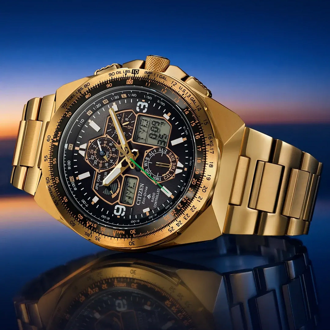 A limited edition CITIZEN Promaster Skyhawk A-T Eco-Drive 46mm watch, one of only 5,200 pieces, featuring a gold-tone metal bracelet, atomic timekeeping, a black dial with both analog and digital displays—all showcased against a blurred sunset background.