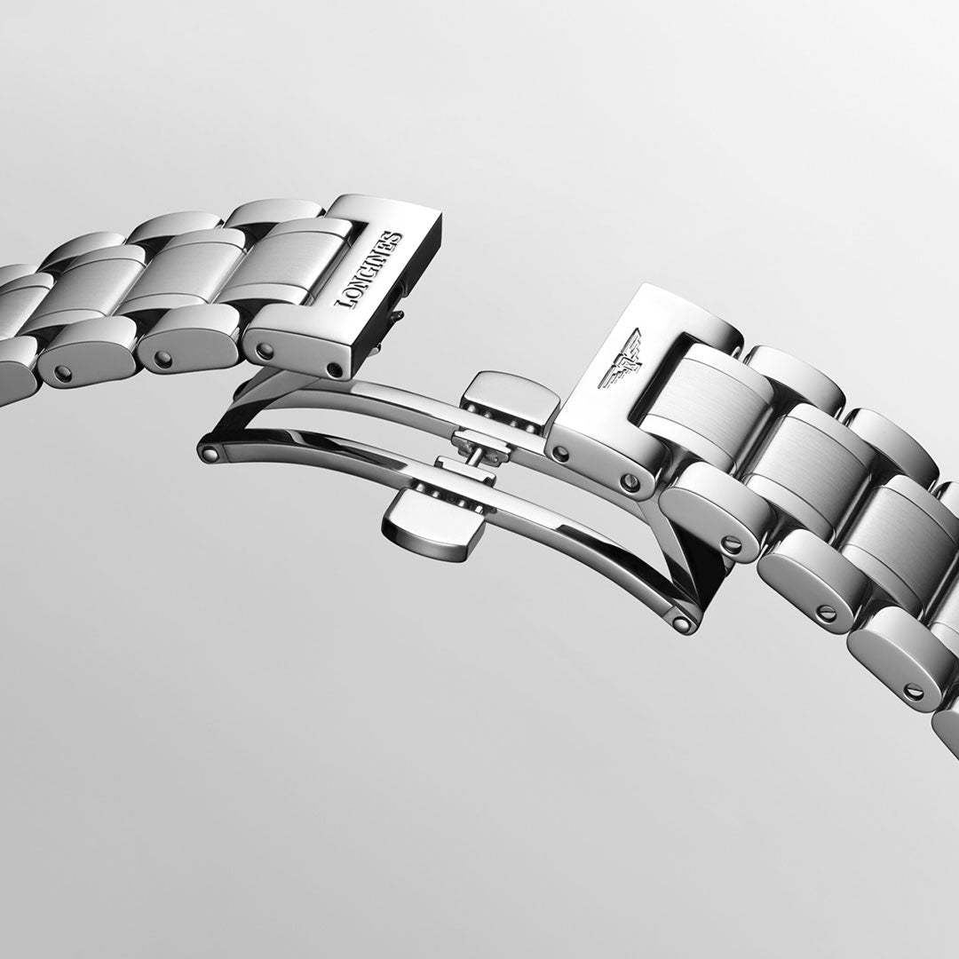 A close-up of a stainless steel bracelet from the Longines Master Collection Automatic Moonphase 40mm Watch highlights the engraved brand name on one side and a winged emblem on the other. This elegant timepiece is elegantly displayed against a smooth, light gray background.