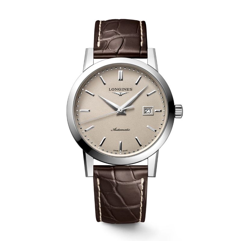 The Longines 1832 Automatic 40mm Watch showcases a beige dial with silver hour markers and includes a date window at the 3 o'clock position. The dial is elegantly marked with "Automatic," and the watch is complemented by a brown leather strap, featuring a durable sapphire crystal.