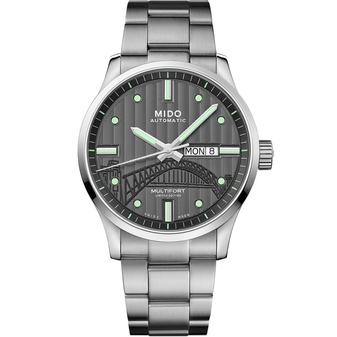 The MIDO Multifort 20th Anniversary Limited Edition Automatic 42mm watch features a black textured dial with green markers, day/date display, decorative bridge design, and a metal band—limited to 1932 pieces.