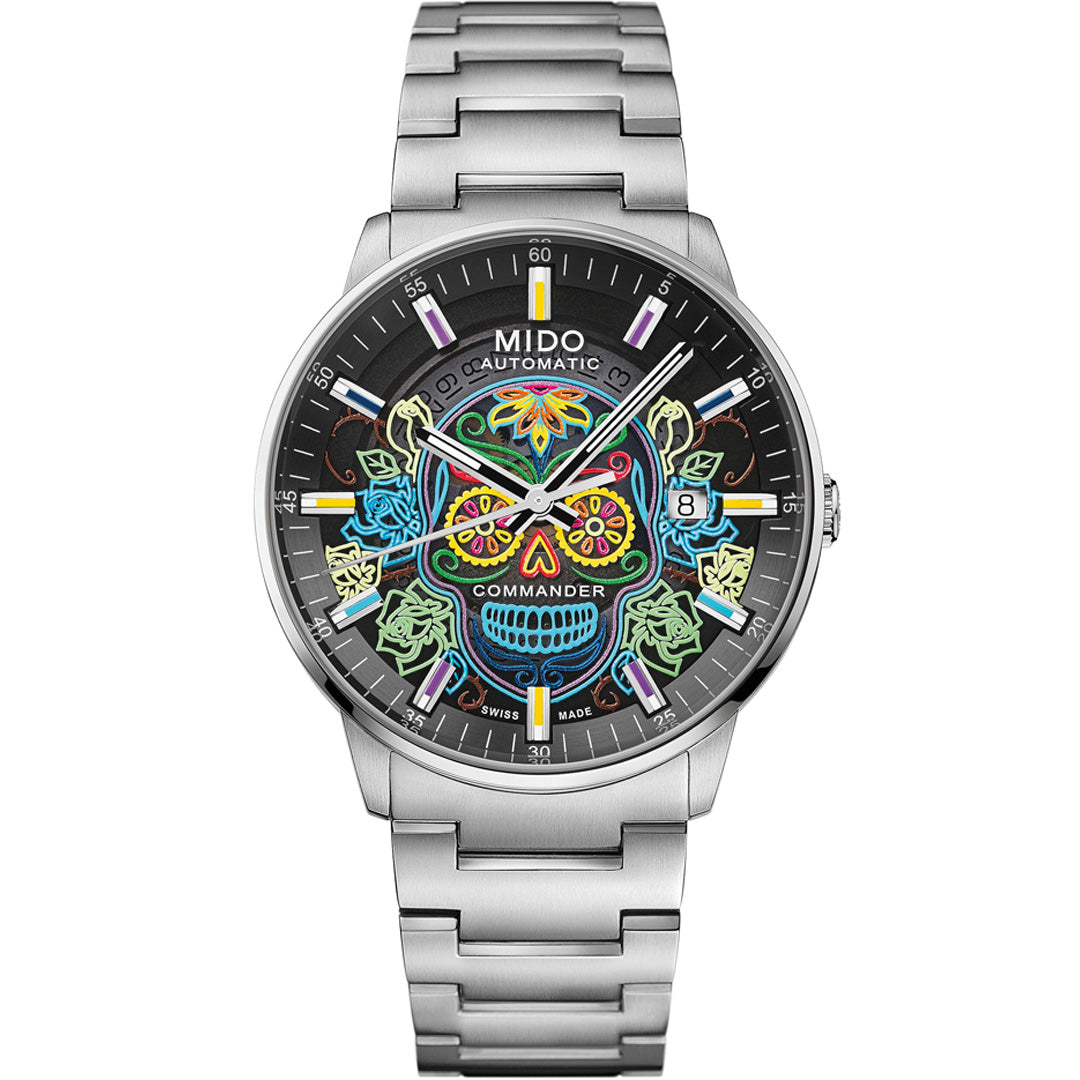 The MIDO Commander Gradient Catrines Automatic 40mm watch features a colorful sugar skull on a transparent dial, date window at 3 o’clock, silver hour markers, and a stainless steel bracelet.