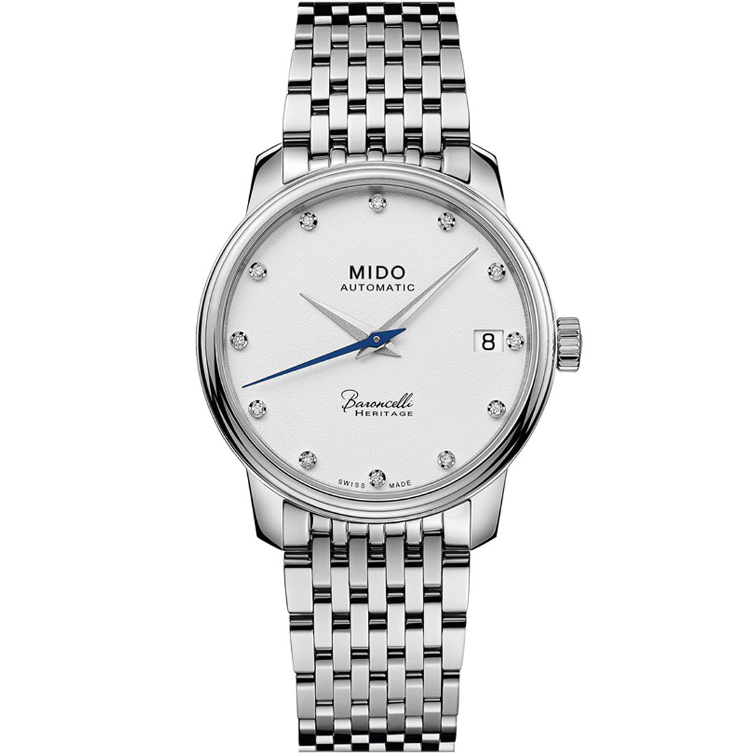 The MIDO Baroncelli III Heritage Lady Automatic 33mm Watch features a silver case, Swiss automatic movement, white dial with diamond hour markers, blue seconds hand, date at 3 o’clock, and a silver link bracelet.