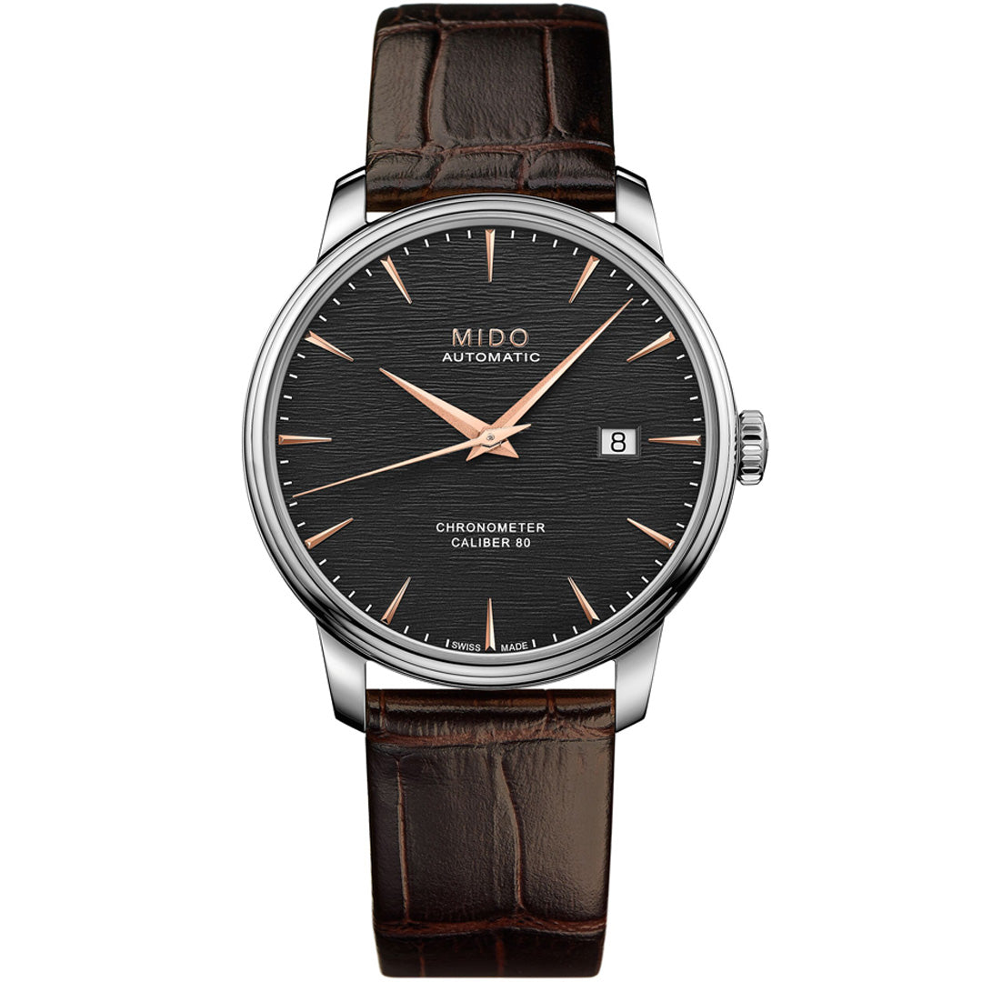 The MIDO Baroncelli III Chronometer Silicon Gent Automatic 40mm Watch features a textured black dial, rose gold hands and markers, date at 3 o’clock, brown leather strap, silver-toned case, and a silicon balance spring for precision.