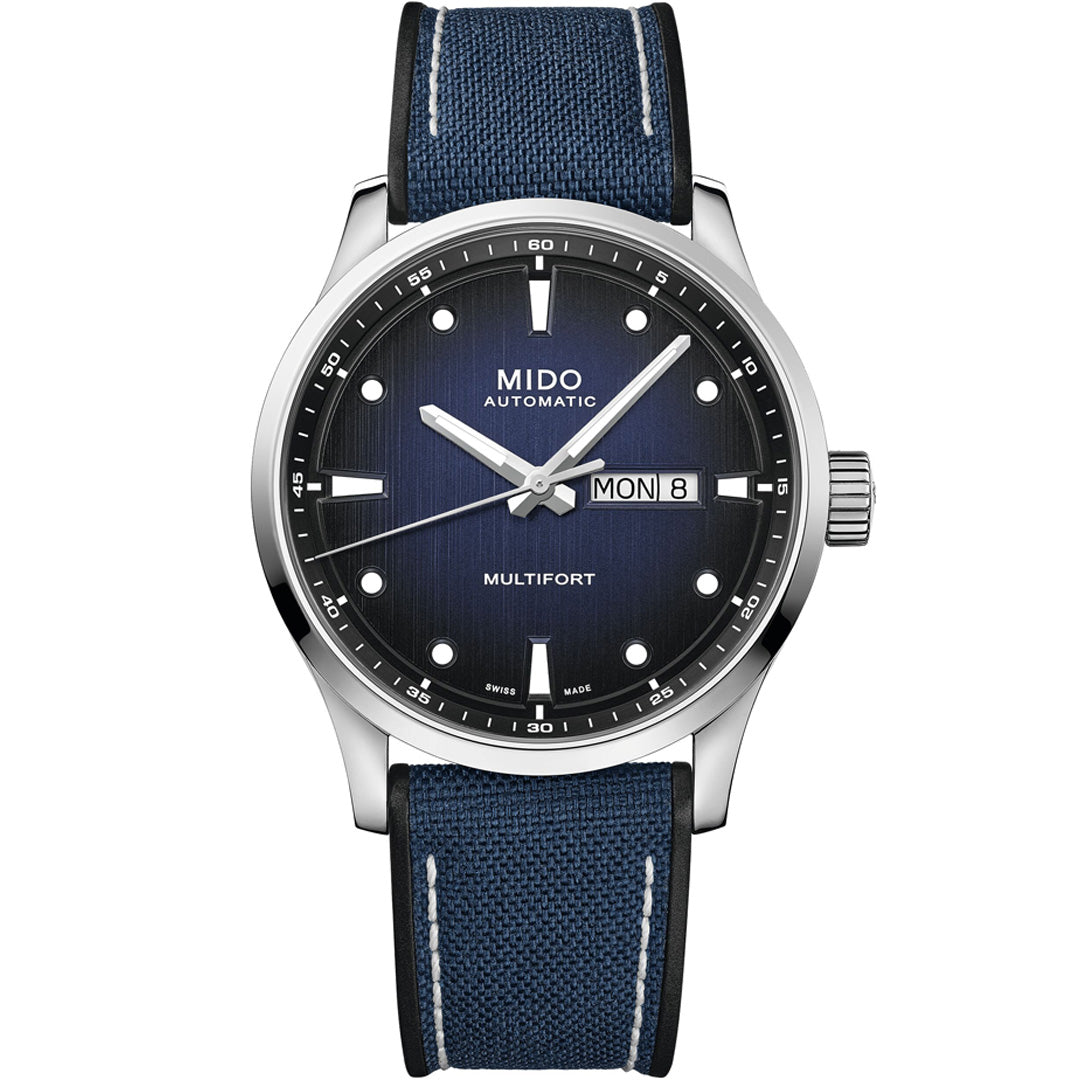 The MIDO Multifort M Automatic 42mm Watch features a blue textured dial, silver markers, day-date display, and blue fabric strap with white stitching. Housed in stainless steel, it runs on Caliber 80 with a Nivachron hairspring.