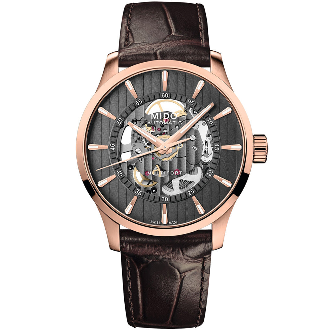 The MIDO Multifort Skeleton Vertigo Automatic 42mm Watch features a rose gold case, brown leather strap, and a partially open black dial that reveals its intricate automatic movement and striking gold accents.