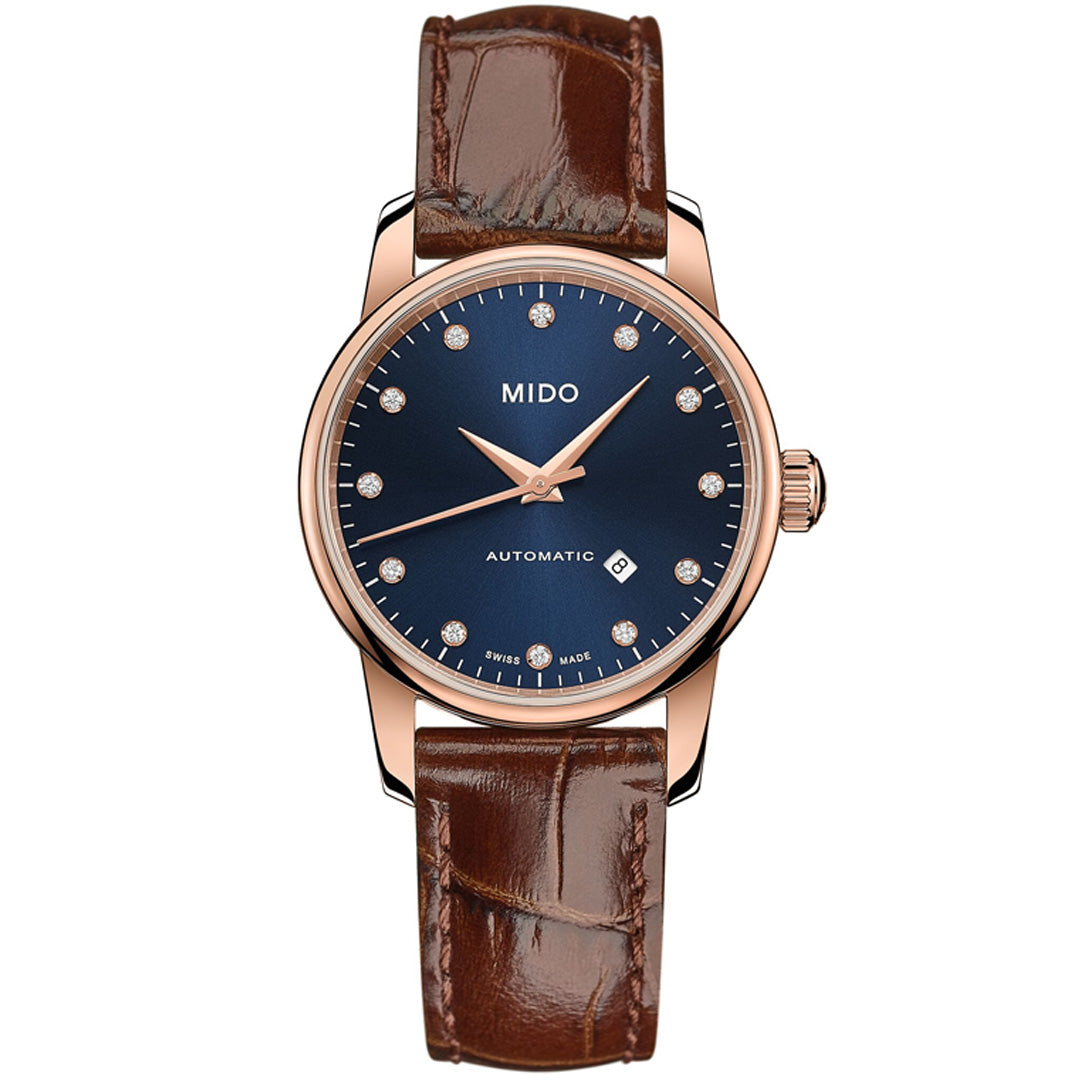 The MIDO Baroncelli II Lady Automatic 29mm features a dark blue dial, gold-tone case, diamond hour markers, brown leather strap, Caliber 80 movement, date display, plus "AUTOMATIC" and "SWISS MADE" on the dial.
