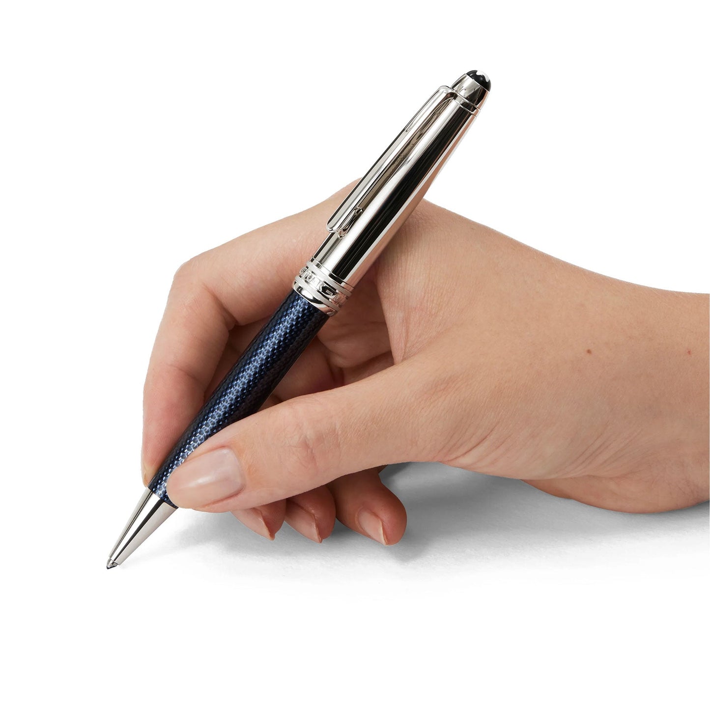 A hand holding the elegant Montblanc Meisterstück Solitaire Doue Blue Hour Classique Ballpoint Pen in silver and blue is poised to write. The pen showcases platinum-coated fittings, a shiny metallic clip, and a textured barrel, set against a white background that echoes the essence of the Blue Hour.