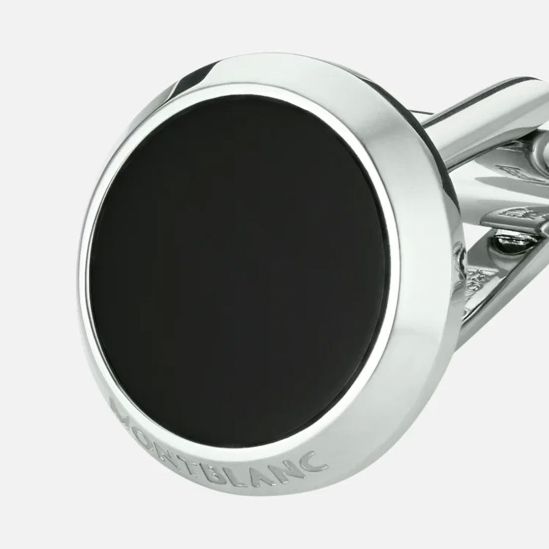 The Montblanc Meisterstück Black Onyx & Stainless Steel Cufflinks showcase a round, silver design centered around a stunning black onyx stone. They feature an engraved edge and are crafted from premium stainless steel, set against a simple light gray backdrop.