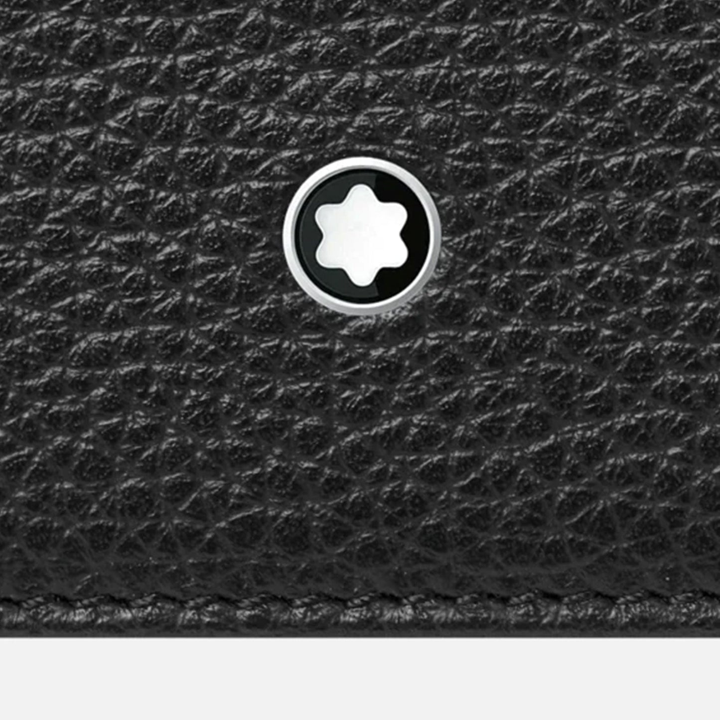 Detailed view of the Montblanc Meisterstück Soft Grain Leather Card Holder, showcasing its textured black leather surface adorned with a small round metal emblem featuring a white star design. An ideal and stylish pocket accessory.