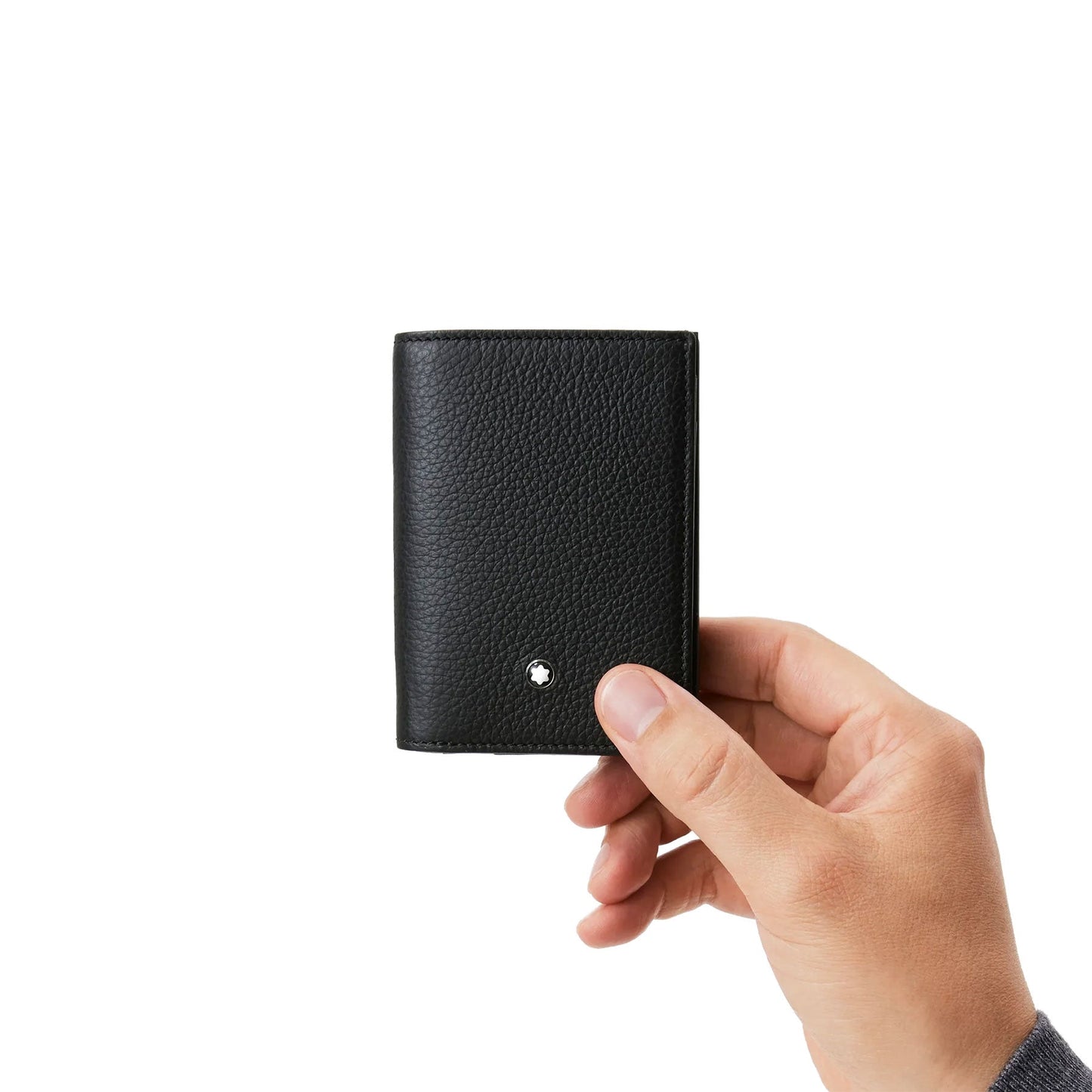 A hand holds the luxurious Montblanc Meisterstuck Soft Grain Leather Business Card Holder with Bill Compartment, crafted from sleek black leather with a textured finish, making it an ideal choice for the modern professional. This elegant accessory includes a metal emblem in the lower front corner, set against a plain white background.
