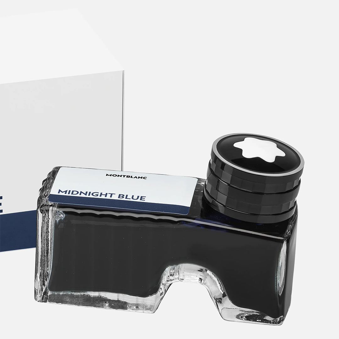 The Montblanc Ink Bottle 60ml in Midnight Blue exudes elegance with its distinctive design, featuring a black cap adorned with the iconic white star emblem. The box, partially visible in the background, complements the ink's deep blue theme, enhancing the allure of this exquisite product from Montblanc.
