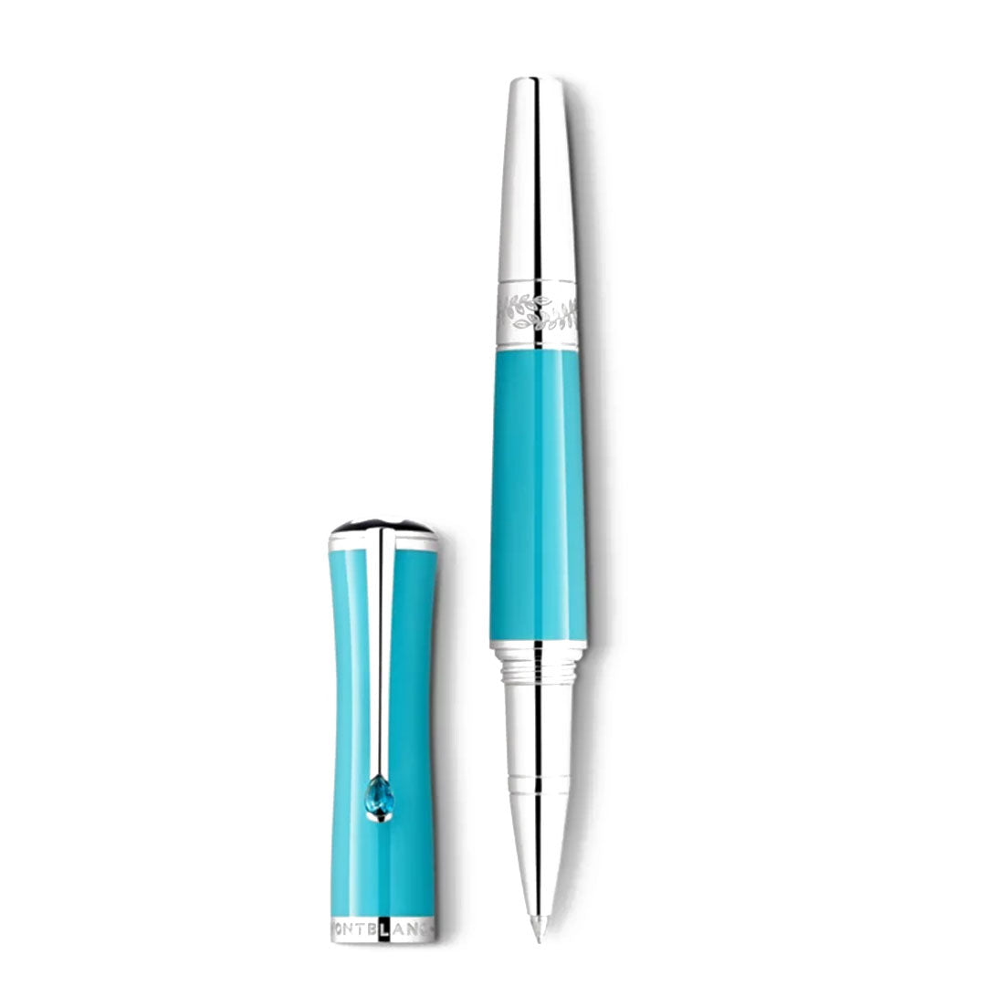 The Montblanc Muses Maria Callas Special Edition Rollerball Pen, in a striking turquoise hue, showcases elegant silver accents and a shiny clip. Without its cap, the pen reveals a fine tip. The cap is adorned with an emblem near the top and features an engraved band at the bottom.