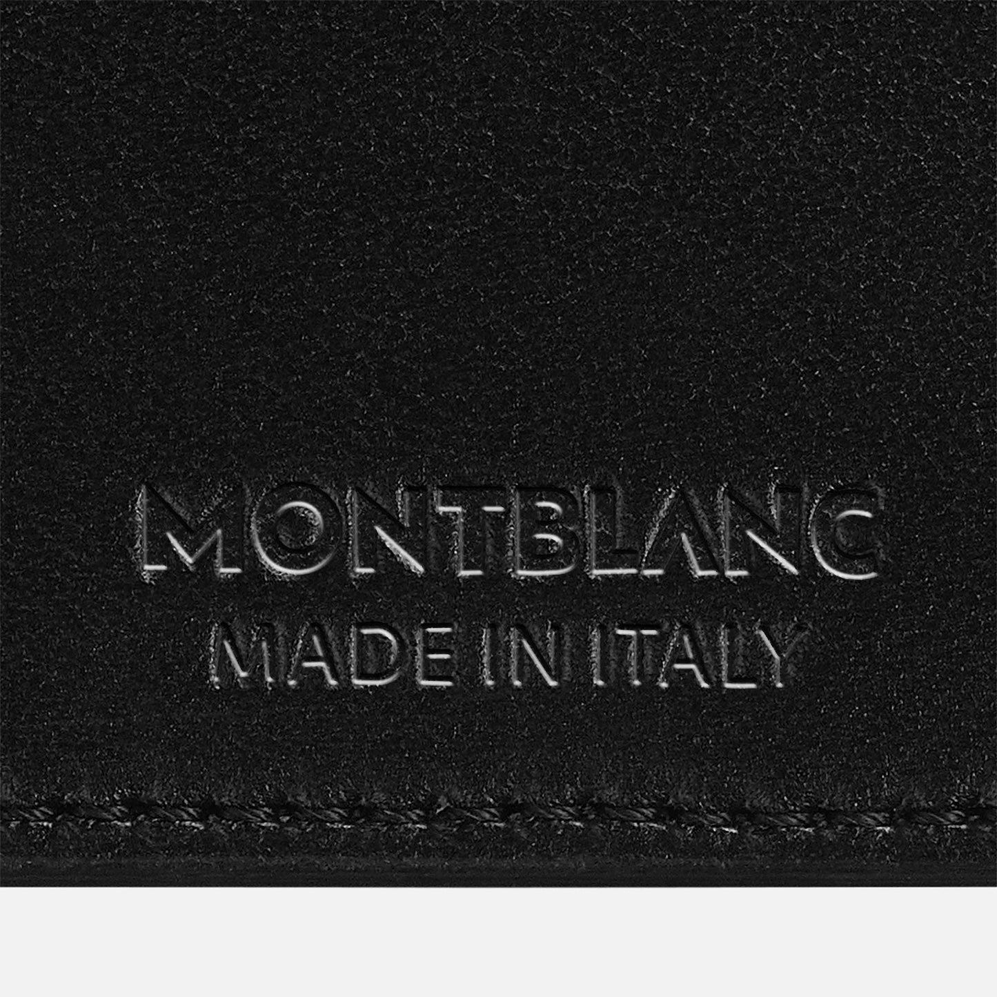 Close-up of a black leather surface showcasing embossed text that reads "Montblanc Made in Italy." This refined piece, part of the Montblanc Extreme 3.0 Leather Card Holder 6cc collection, embodies the pinnacle of luxury craftsmanship.