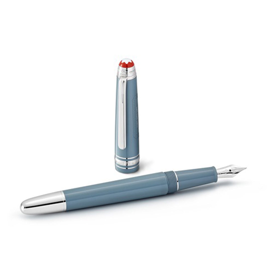 A Montblanc writing instrument rests elegantly against a plain white background: the Meisterstück x Olympic Heritage Chamonix 1924 Classique Fountain Pen, featuring a gray body with a silver nib, lies beside its matching cap adorned with a red and white emblem on top, embodying the iconic style reminiscent of the Meisterstück centenary.